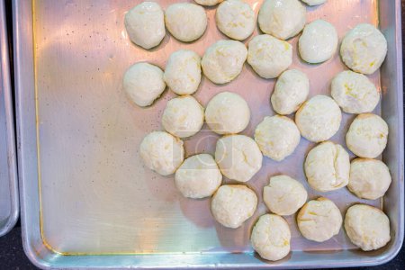Dough balls on metal tray with olive oil to make sure it is not sticking and can be shaped later to be used and stuffed
