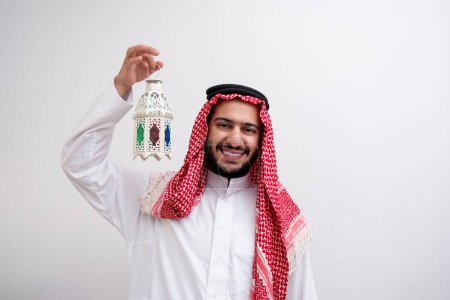 Draped in the dignified attire of Kandoura and Keffiyeh, an Arabic man extends a symbol of hospitality and generosity by holding Fanous. Against a backdrop of purity, to illuminate the essence of Eid