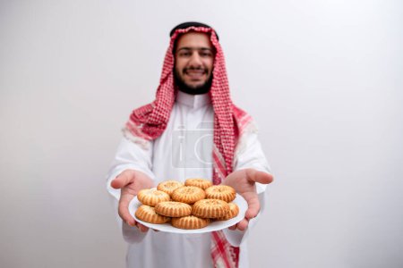 In a gesture of hospitality and generosity, an Arabic man proudly presents a plate of Maamoul, symbolizing the warmth and abundance of Eid celebrations. Clad in the traditional Kandura and Keffiyeh