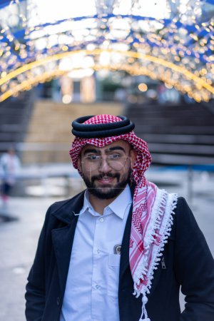 portrait for arabic young male wearing traditional clothes with modern background and blurred lights