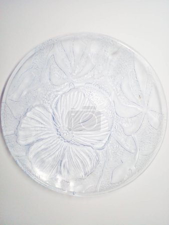 Transparent glass plate on white background. Glass plate with floral motif.