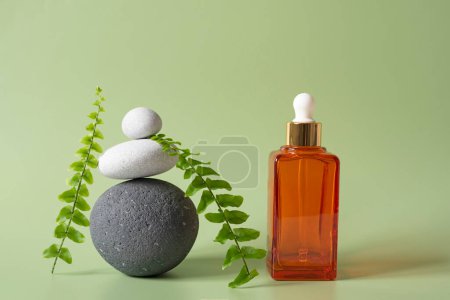Photo for Pyramid of stones on a green background  fern leaves, and a glass container for cosmetics.  Spa concept, balance and tranquility - Royalty Free Image