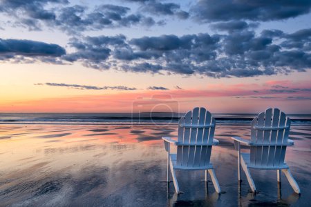 Photo for Two white wooden armchairs on the edge of the ocean at dawn. Gentle pink dawn. USA. Maine. - Royalty Free Image