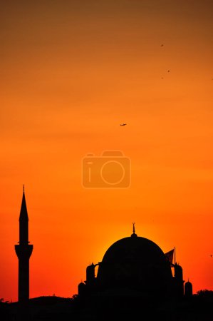 Foto de Istanbul mosques silhouettes in sunset orange sunlight. And the plane is in the sky. - Imagen libre de derechos