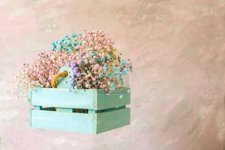 Delicate bouquet with pink small flowers in a in a wooden box on a light background