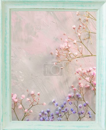 Delicate flower twigs on a soft pink background in a vintage light wooden frame