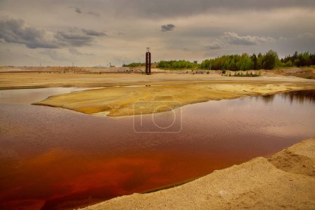 Photo for Granite quarry for iron ore extraction. Pond with red water after mining. Industrial landscape. Problems of ecology and environment. - Royalty Free Image