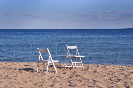 Foto de Dos sillas blancas de madera en la playa con vistas al mar y el cielo azul. playa desierta. - Imagen libre de derechos