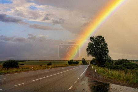 Photo for Asphalt deserted road after rain, fields and a colorful rainbow - Royalty Free Image