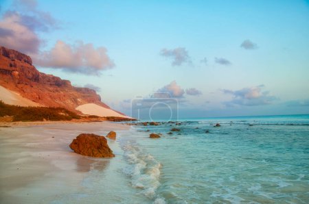 Foto de Hermosa mañana en una playa salvaje en el océano y las montañas rocosas en la orilla. Isla Socotra. luz solar suave - Imagen libre de derechos