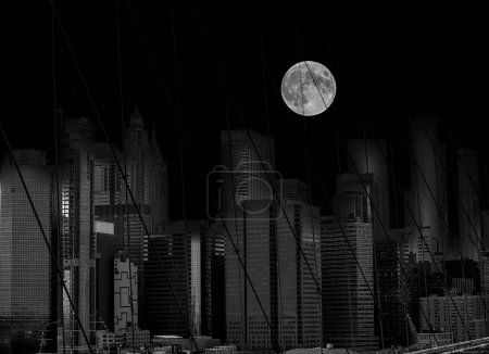    A huge moon above the skyscrapers behind the bars of the Brooklyn Bridge. New. York. Manhattan. black and white night photo withelements of surrealism.