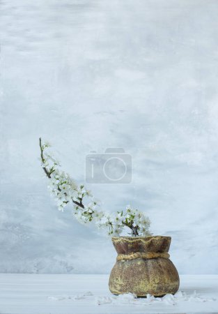 Un bouquet aux branches printanières fleuries de cerisier et de sakura aux délicates fleurs blanches dans une cruche sur un fond pastel doux. photo artistique.