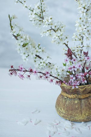 A bouquet with blooming spring branches of cherry and sakura with delicate white and pink flowers in a jug on a soft pastel background. artistic photo.