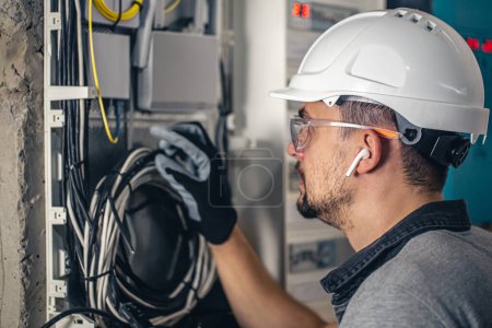 Foto de Hombre, un técnico eléctrico trabajando en una centralita con fusibles. Instalación y conexión de material eléctrico
. - Imagen libre de derechos