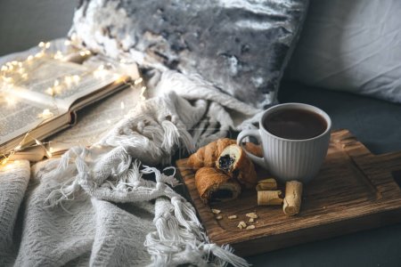 Photo for Cozy composition with a cup of tea, candles and books in bed, copy space. - Royalty Free Image