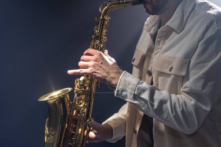 Téléchargez les photos : Musicien masculin sur scène joue le saxophone sombre avec de la fumée, espace de copie. - en image libre de droit
