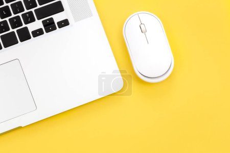 Computermaus und Laptop auf gelbem Hintergrund isoliert, flach gelegt, Kopierraum.