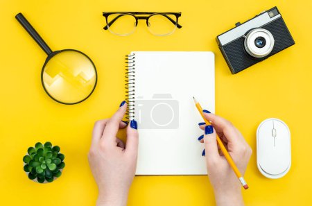 Photo for Blank notepad in female hands on a yellow background, flat lay, concept of hobies, work and creativity, copy space. - Royalty Free Image