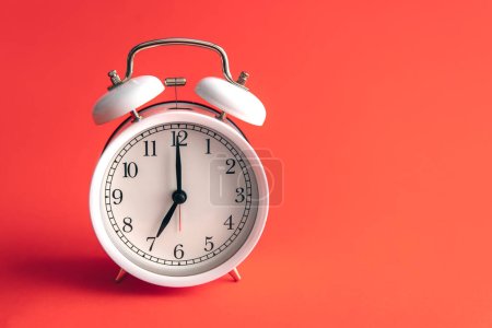 Photo for White alarm clock on a blurred red background, copy space. - Royalty Free Image