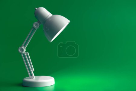 Téléchargez les photos : Lampe de table blanche sur fond vert. Une petite lampe jouet, concept d'apprentissage, de lecture et d'éducation, espace de copie. - en image libre de droit