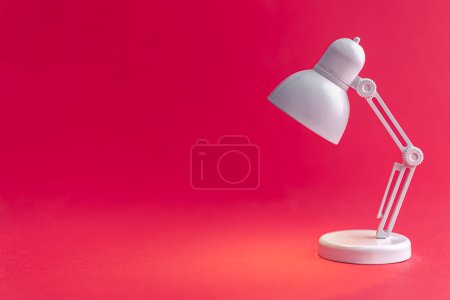 Téléchargez les photos : Lampe de table blanche sur fond Viva Magenta. Une petite lampe jouet, concept d'apprentissage, de lecture et d'éducation, espace de copie. - en image libre de droit