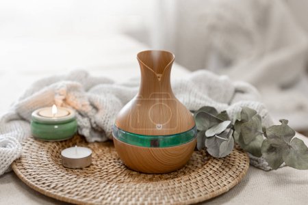 Cozy spa composition with aroma oil diffuser lamp on a blurred background.