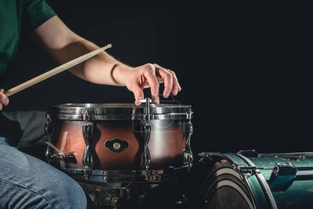 Photo for A male drummer plays the snare drum on a dark background, a musical percussion instrumentman, copy space. - Royalty Free Image