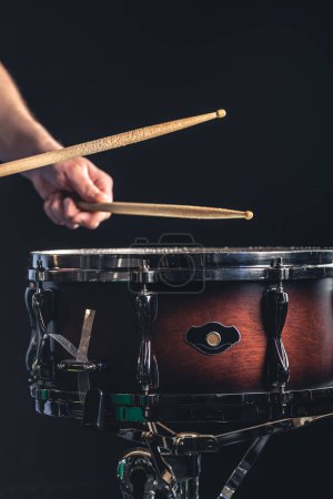Photo for A male drummer plays the snare drum on a dark background, a musical percussion instrumentman. - Royalty Free Image