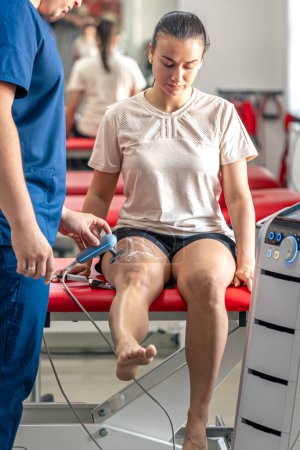 Médico usando máquina para tratar las articulaciones de rodilla de un paciente, tecnología T-CaRe, terapia resistiva y capacitiva.