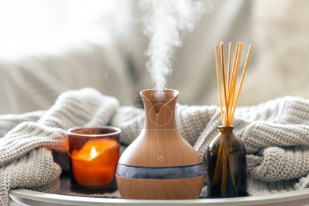 Photo for Aroma oil diffuser lamp with the stick perfume, knitted element and candle on a blurred background, copy space. - Royalty Free Image