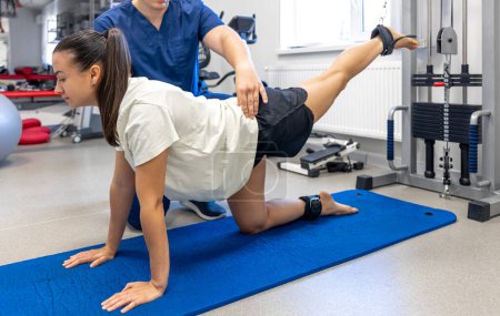 Foto de Mujer hace ejercicio para estirar los músculos, paciente realizando un ejercicio de entrenamiento de fuerza asistida por un kinesiólogo. - Imagen libre de derechos