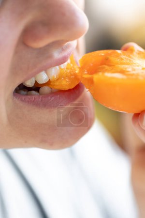 Téléchargez les photos : Plan détaillé d'une femme qui mord une tomate mûre jaune, gros plan. - en image libre de droit