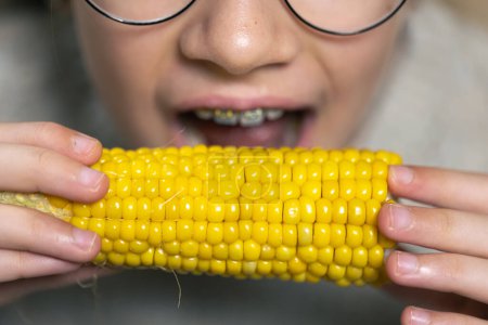 Téléchargez les photos : Plan détaillé d'une fille mangeant du maïs, gros plan. - en image libre de droit
