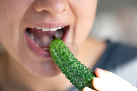 Téléchargez les photos : Plan détaillé d'une femme mange du concombre vert frais, gros plan. - en image libre de droit
