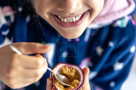 Téléchargez les photos : Petite fille mangeant des fruits de la passion, bouche gros plan, concept de saine alimentation et de vitamines. - en image libre de droit