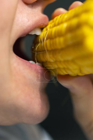 Téléchargez les photos : Plan détaillé d'une femme mangeant du maïs mûr, gros plan. - en image libre de droit