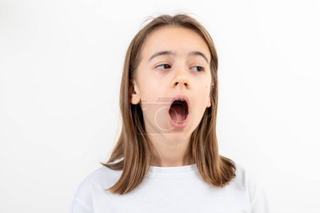 Photo for A girl on a white background yawns from boredom, a tired student, a sleepy child. - Royalty Free Image