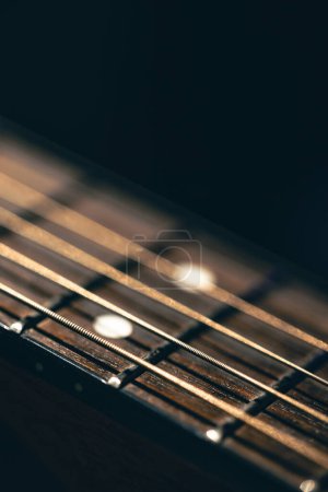 Foto de Parte de una guitarra acústica, diapasón de guitarra sobre fondo negro. Primer plano de cuerdas de guitarra, macro shot. - Imagen libre de derechos
