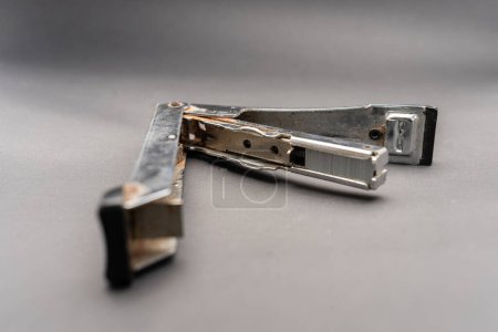 A used rusty stapler. A tool for holding together a number of pieces of paper which are usually made of metal.Isolated on dark background.