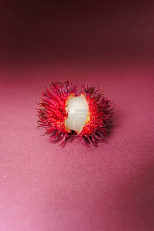 Abundance of fresh red rambutans for sale in the Indonesian market isolated on red background.