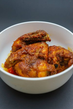 Sambal ayam casero balado o pollo frito picante es comida tradicional de Padang, Sumatra Occidental. Servido en tazón y aislado sobre fondo negro.