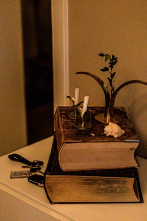 A rustic candle stand atop a stack of vintage books.