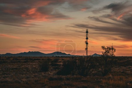 Silhouetted communication towers stand out against a fiery sunset sky.