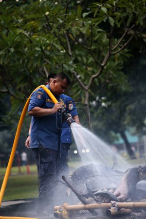 Foto de Yakarta, Indonesia. 21 de abril de 2024. Equipo de bomberos rocía agua en un Ogoh-ogoh ardiente en TMII, Yakarta - Imagen libre de derechos