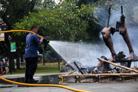 Téléchargez les photos : Jakarta, Indonésie. 21 avril 2024. Une équipe de pompiers pulvérise de l'eau sur un Ogoh-ogoh flamboyant à TMII, Jakarta - en image libre de droit