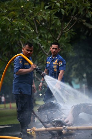 Photo for Jakarta, Indonesia. April 21, 2024. TMII, Jakarta: Firefighters extinguish flames on a burned Ogoh-ogoh - Royalty Free Image