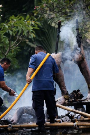 Foto de Yakarta, Indonesia. 21 de abril de 2024. Bomberos rocían agua de alta presión para extinguir el fuego que quemó Ogoh-ogoh en la atracción turística TMII, Yakarta. - Imagen libre de derechos