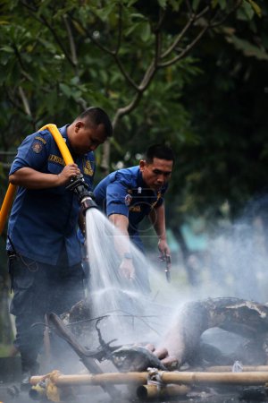 Foto de Yakarta, Indonesia. 21 de abril de 2024. Bomberos rocían agua de alta presión para extinguir el fuego que quemó Ogoh-ogoh en la atracción turística TMII, Yakarta. - Imagen libre de derechos