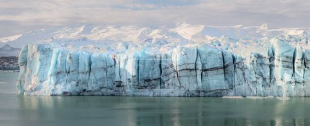 Un grand iceberg domine le centre d'un plan d'eau, mettant en valeur sa grandeur et son immensité.