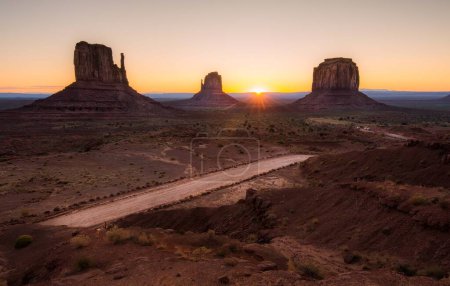 The sun descends below the horizon, casting a warm glow across the vast desert landscape.